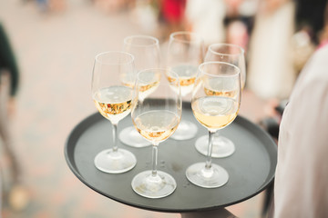 Waiter serving glasses with champagne on a tray