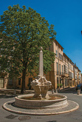 Street with buildings and fountain in sunny afternoon in Aix-en-Provence, a pleasant and lively town in the French countryside. In the Bouches-du-Rhone department, Provence region, southeastern France
