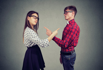 Annoyed angry man and woman facing relationships problems, pointing fingers each other blaming for...