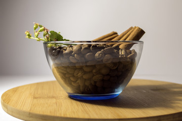 Obraz na płótnie Canvas Coffee beans with cinnamon in a transparent plate