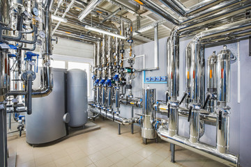 The interior of an industrial boiler house with a multitude of pipes, barrels and sensors