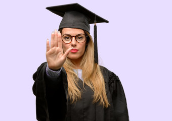 Young woman university graduate student annoyed with bad attitude making stop sign with hand, saying no, expressing security, defense or restriction, maybe pushing