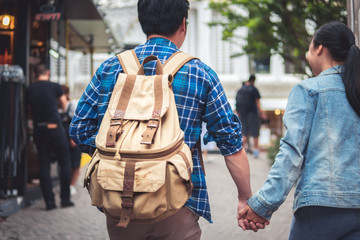 Couple holding hand travel in town and walking street. Honey moon concepts. Man and women in jean suit.