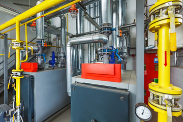 The interior of an industrial boiler house with a multitude of pipes, boilers and sensors