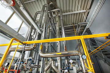 The interior of an industrial boiler house with a multitude of pipes, boilers and sensors