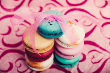 Tasty different colored macarons on pink background   