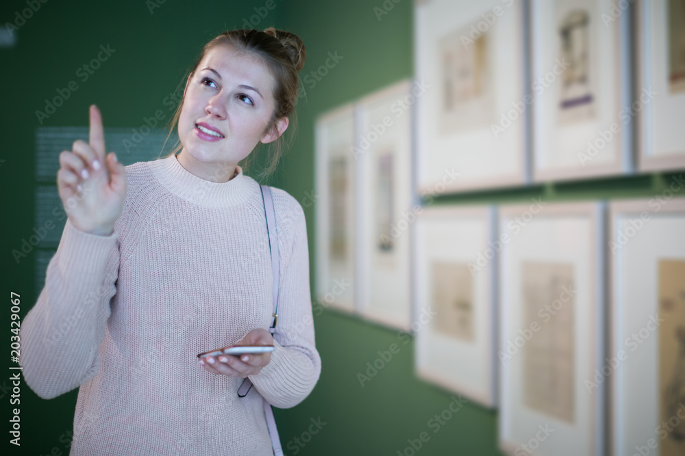 Wall mural young female visitor with smartphone in historical museum