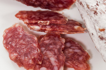 Macro shot of sliced tasty dry italian sausage isolated on white background.