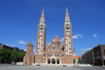 Fototapeta na wymiar The Votive Church and Cathedral of Our Lady of Hungary is a twin-spired roman catholic cathedral in Szeged, Hungary. It lies on Dom Ter square beside the Domotor tower.