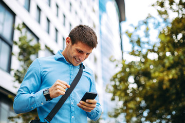 Young businessman online via smartphone in the city