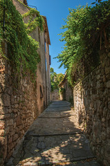 Fototapeta na wymiar View of stone houses in a narrow alley under blue sky, at the gorgeous medieval hamlet of Les Arcs-sur-Argens, near Draguignan. Located in the Provence region, Var department, southeastern France