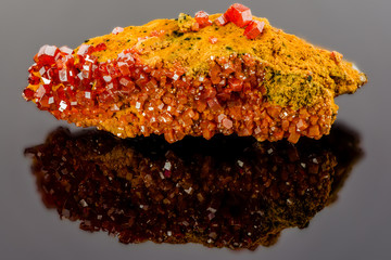 Nice looking piece of vanadinite mineral is reflecting in the dark mirror-like surface