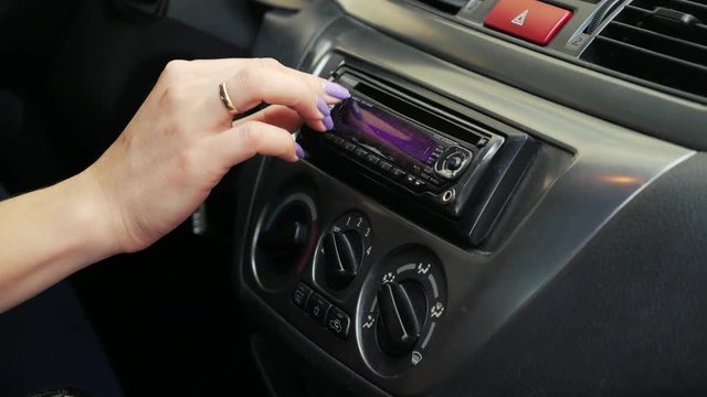 A woman driver adjusts the radio in the car