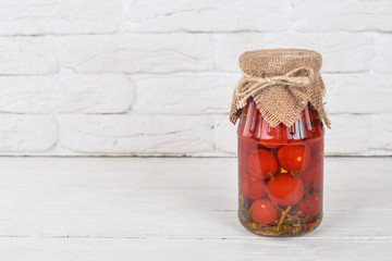 Marinated cherry tomatoes in a jar. Stocks of food. Top view. On a wooden background. Copy space.