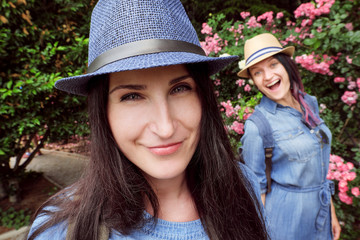 Two girls laugh, posing in the garden with blooming roses on a fisheye lens