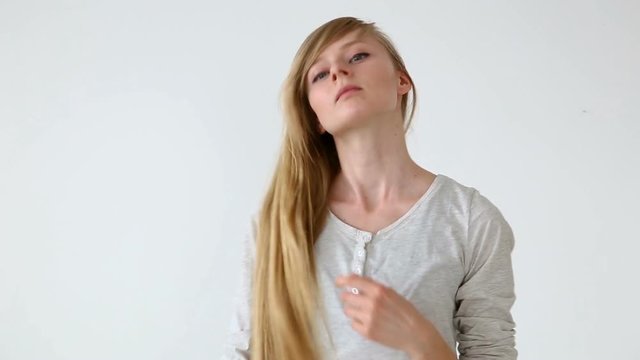 beautiful long-haired girl of European appearance with blond hair making different hairstyles over white background