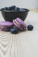 The Black bowl full of blueberries and blueberries macaroons. Vintage filter.