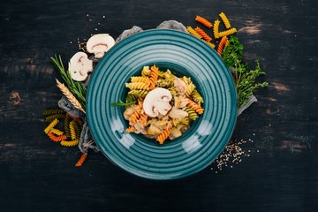 Pasta with mushrooms and chicken. On a wooden background. Italian cuisine. Top view. Copy space.