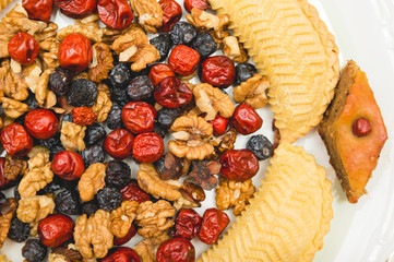 Sweets and desserts for the Novruz holiday on plate - shekerbura, baklava, walnuts and dried fruits