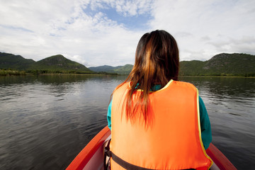 Asian women life jacket orange color on the boat travel in Reservoir Tha Thung Na Kanchanaburi landmark Thailand.