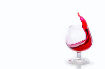 Splash of red wine in a glass on a white background