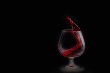 Splash of red wine in a glass on a black background