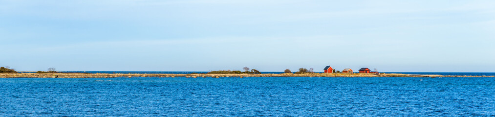 Panorama over the coast outside the small village of Kalla on Oland, Sweden. Small fishing sheds on the outer edge of a headland on a calm and sunny day in spring.