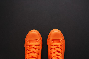 Stylish orange sneakers on dark background