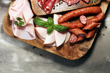 Food tray with delicious salami, ham,  fresh sausages and herbs. Meat platter with selection