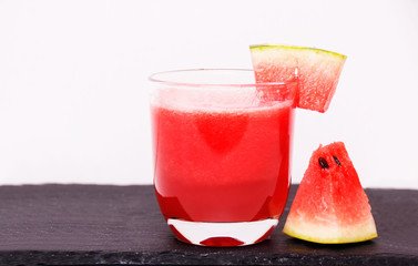 Watermelon juice with slice of watermelon on and beside the glass