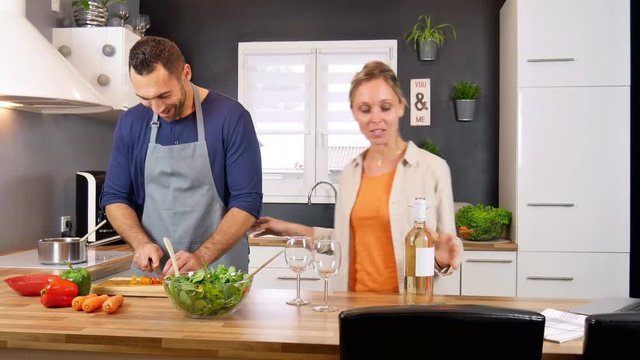 happy cheerful young couple cooking organic vegetables together at home with white wine