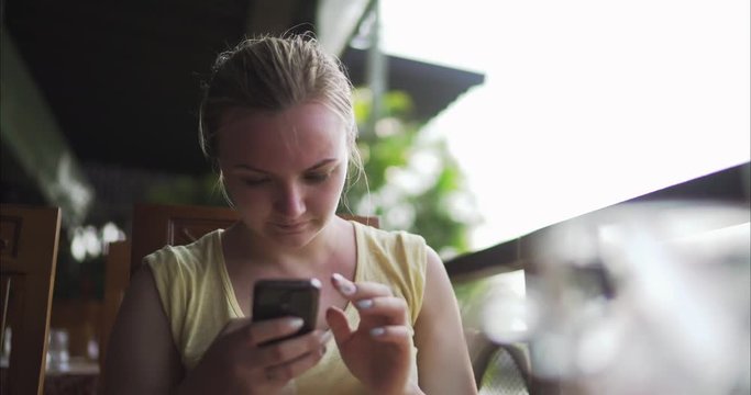 A girl in a cafe with a phone in her hand.