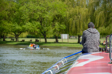 Retired lonely man sat on bow of boat wearing grey jumper with gray hair contemplating the...
