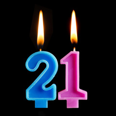 Burning birthday candles in the form of 21 twenty one for cake isolated on black background. The concept of celebrating a birthday, anniversary, important date, holiday