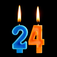 Burning birthday candles in the form of 24 twenty four for cake isolated on black background. The...