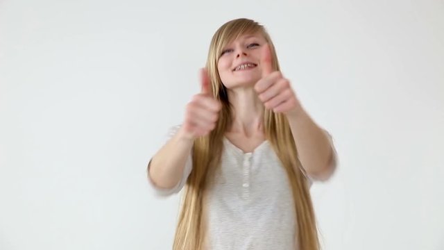 beautiful long-haired girl of European appearance with blond hair showing thumbs up over white abackground