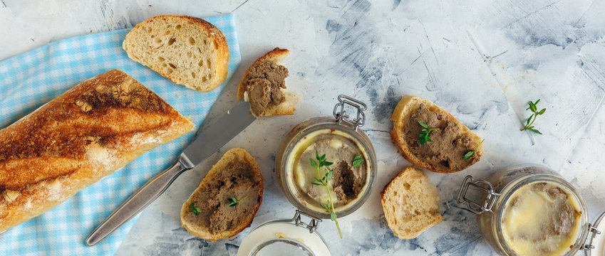 Homemade beef liver pate in a glass jar and baguette slices with pate.