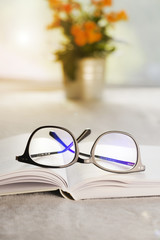Stylish black glasses on a book. Blurred background.