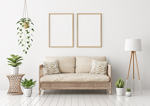 Home interior poster mock up with two vertical empty wooden frames, wicker rattan sofa, plants and lamp in living room with white wall. 3D rendering.