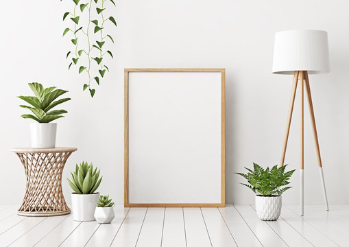 Home interior poster mock up with vertical empty wooden frame standing on floor, wicker rattan table, green plants and lamp in living room with white wall. 3D rendering.