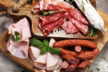 Food tray with delicious salami, ham,  fresh sausages and herbs. Meat platter with selection