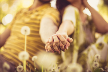  Close up image of couple holding hands.  At nature.