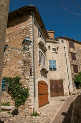 View of alley with stone houses on a blue sunny day in Saint-Paul-de-Vence, a lovely well preserved medieval hamlet near Nice. In Alpes-Maritimes department, Provence region, southeastern France