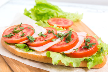 baguette sandwich with ham, tomatoes and lettuce