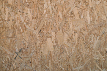 Natural pressed sawdust close-up. Background image of sheet of plywood with fragments of compressed sawdust. Wooden texture template.