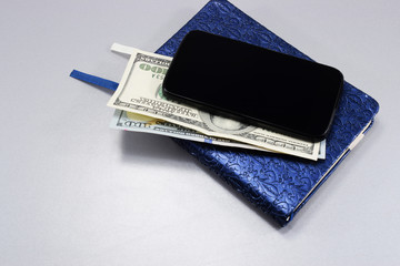 on desk in office, notebook, dollars and cell phone lie on stole