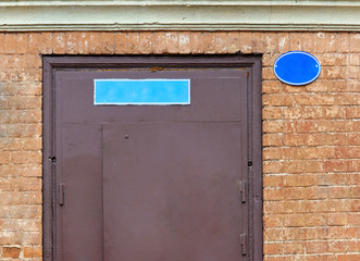 The nameplate on the house on the street. A sign on the stone wall outside on the street.