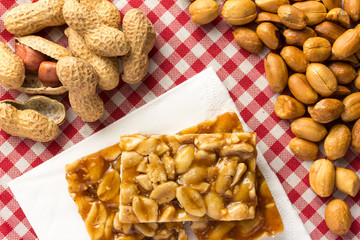 Candy with peanut: Pe de Moleque in Brazil and Chikki in India. Sweet food of Festa Junina, a typical brazilian party. Snack on napkin, red plaid table.