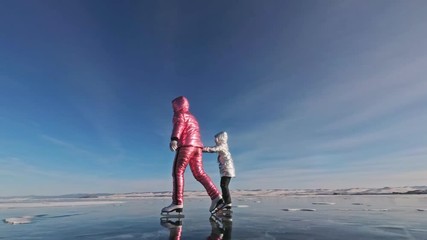 Family is ice skating at day. Girls to ride figure ice skates in nature. Mother and daughter riding together on ice in cracks. Outdoor winter fun for athlete nice winter weather. People on ice skates - Powered by Adobe