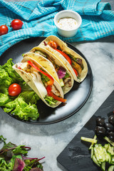Fresh delicious mexican tacos and food ingredients on concrete rustic background